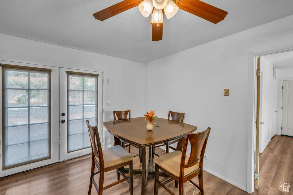 Dining room with french doors, wood finished floors, and a ceiling fan