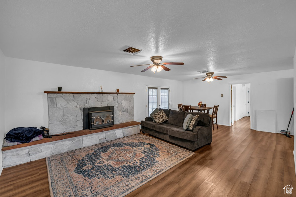 Living room featuring ceiling fan, wood finished floors, and a fireplace