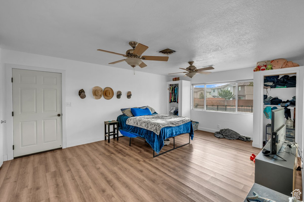Bedroom with light wood finished floors, a textured ceiling, and a ceiling fan