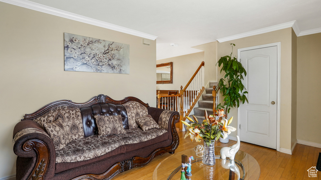 Living room featuring wood-type flooring, crown molding, and stairs