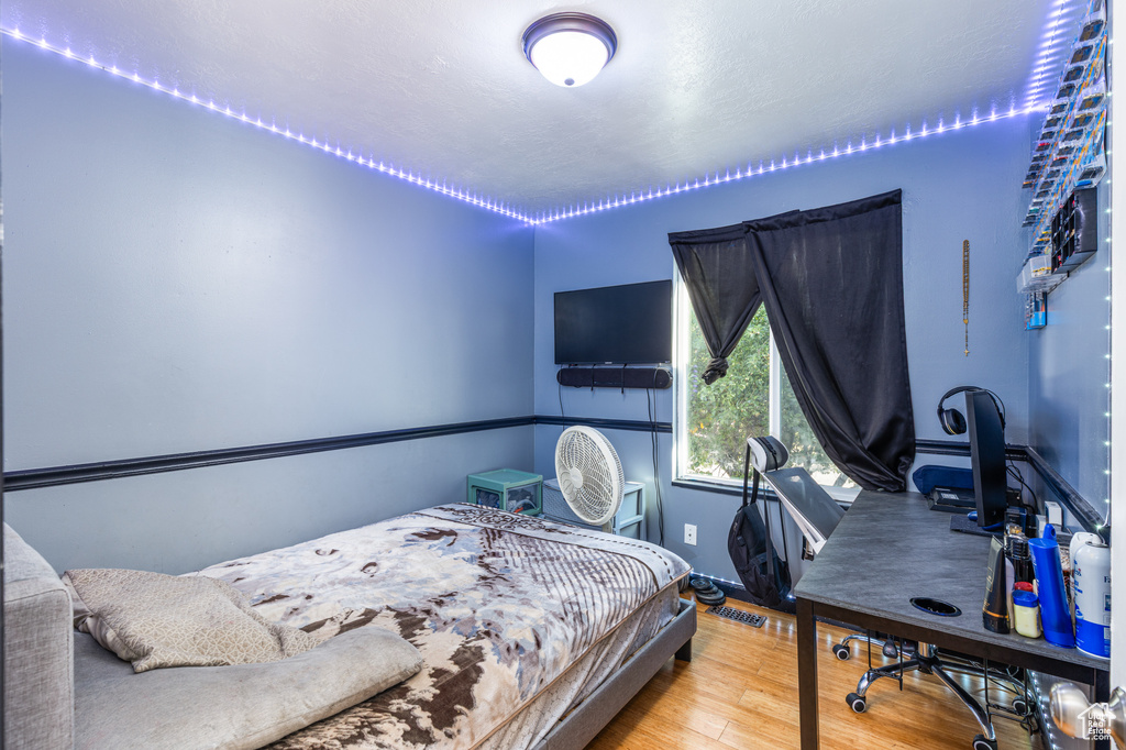 Bedroom with wood finished floors and a desk