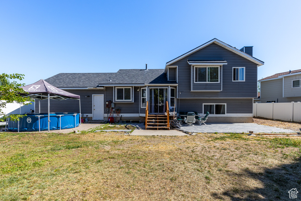 Back of house with entry steps, an outdoor pool, a patio area, a chimney, and roof with shingles