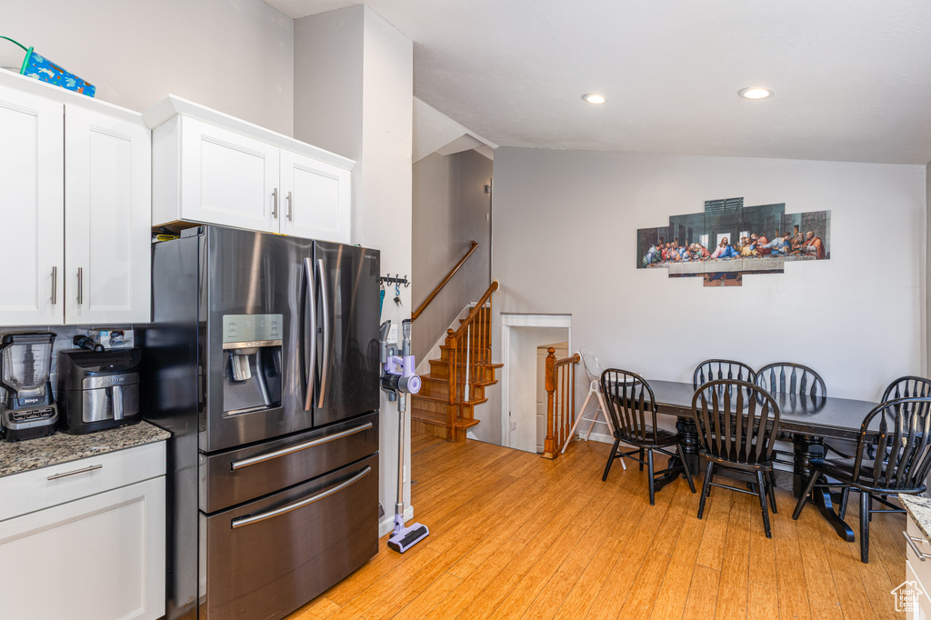Kitchen with stainless steel fridge with ice dispenser, white cabinetry, light stone counters, light wood-type flooring, and recessed lighting