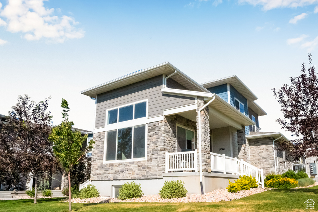 View of home's exterior featuring covered porch, stone siding, and a lawn