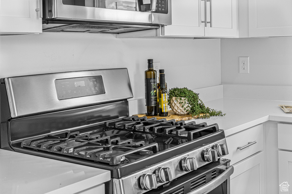 Kitchen view of stainless steel appliances, white cabinets, and light countertops