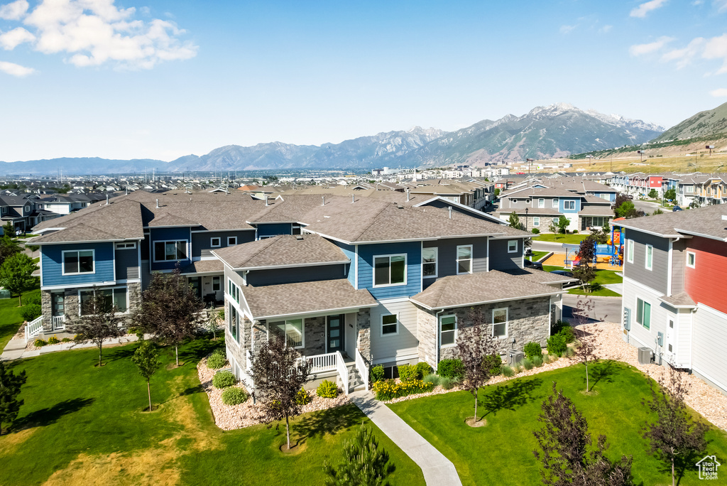 View of front facade with a residential view, stone siding, a mountain view, roof with shingles, and a front yard