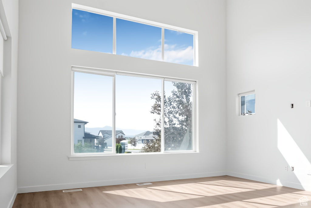 Spare room featuring wood finished floors, a high ceiling, and baseboards