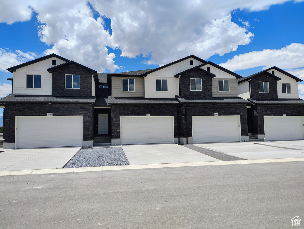 View of front of property featuring an attached garage, board and batten siding, and driveway