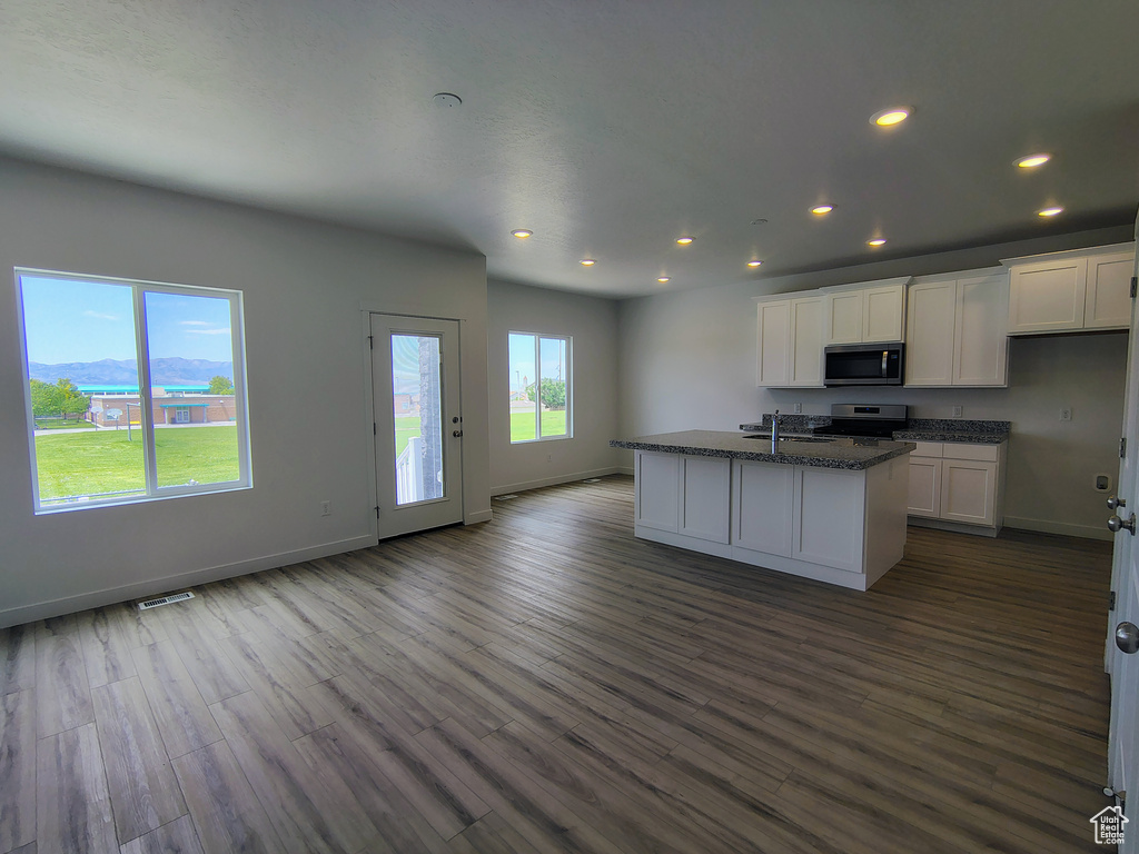 Kitchen featuring stainless steel microwave, stove, white cabinets, recessed lighting, and dark wood-type flooring