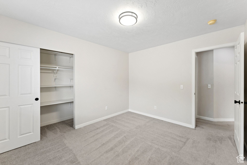 Unfurnished bedroom featuring carpet flooring, a closet, and a textured ceiling