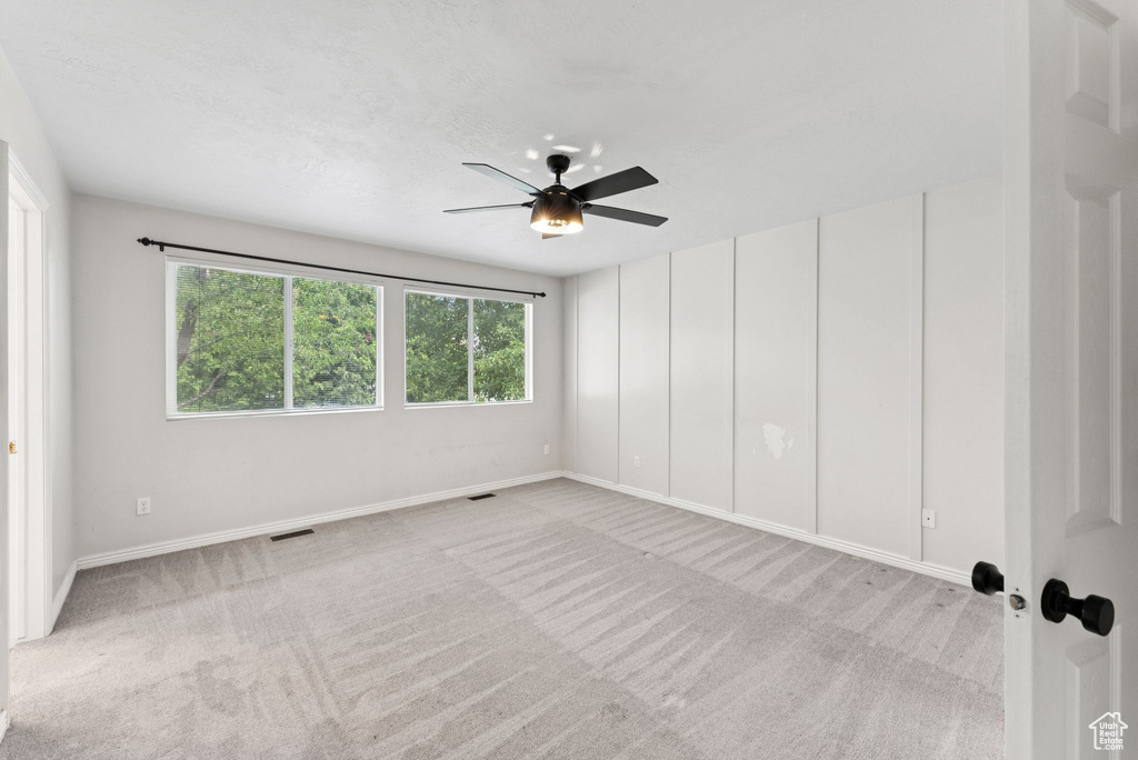 Empty room with carpet floors and a ceiling fan
