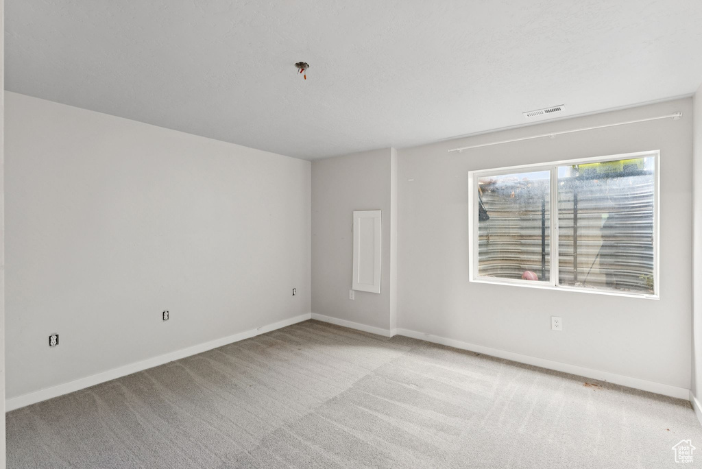 Carpeted empty room featuring baseboards and a pendent fire sprinkler