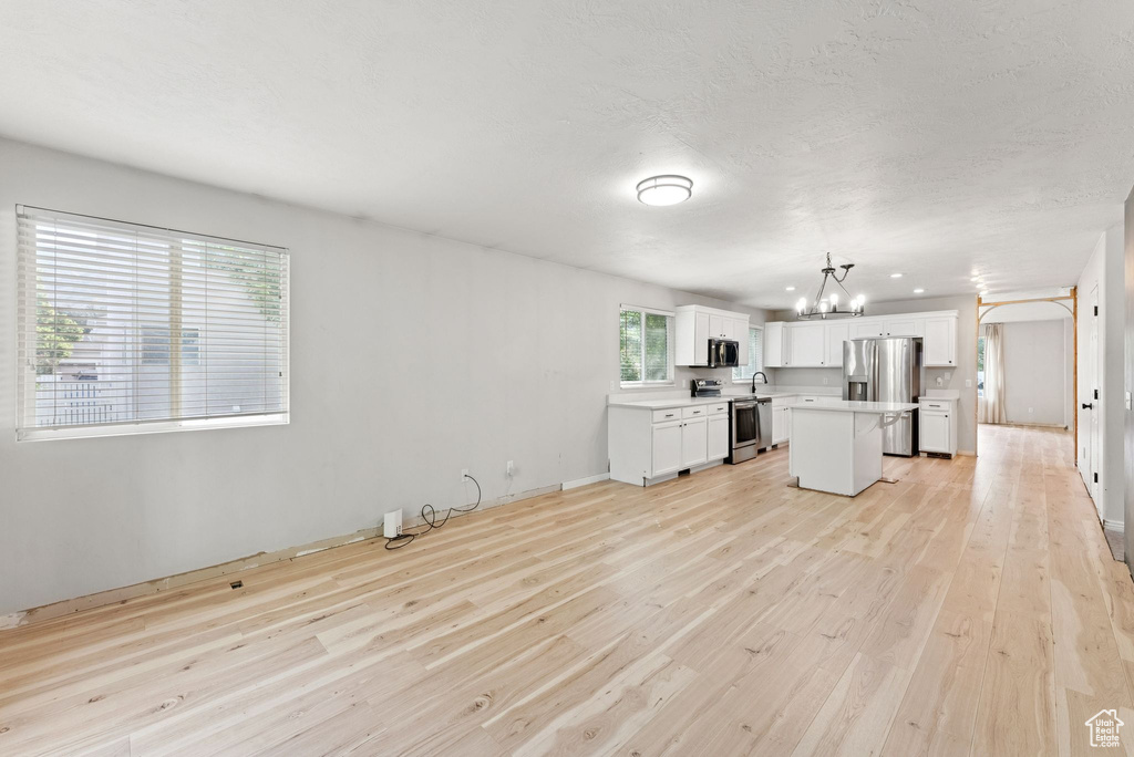 Unfurnished living room with a chandelier and light wood-style floors