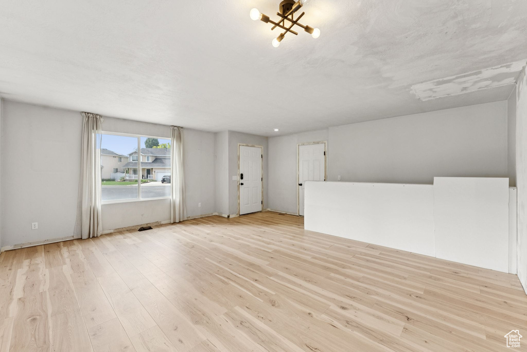 Unfurnished living room with light wood-style floors and a chandelier