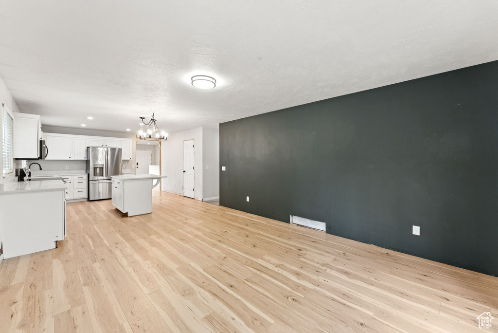 Unfurnished living room with a chandelier and light wood-style floors