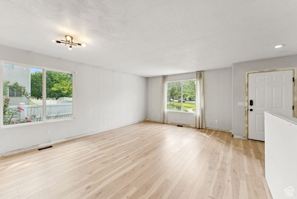 Unfurnished living room featuring plenty of natural light, light wood finished floors, and recessed lighting