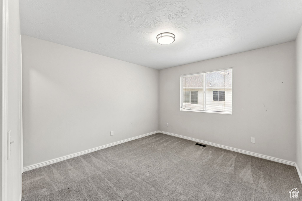 Carpeted empty room featuring baseboards and a textured ceiling