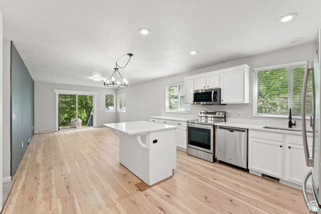 Kitchen with stainless steel appliances, light countertops, light wood-style flooring, white cabinetry, and recessed lighting