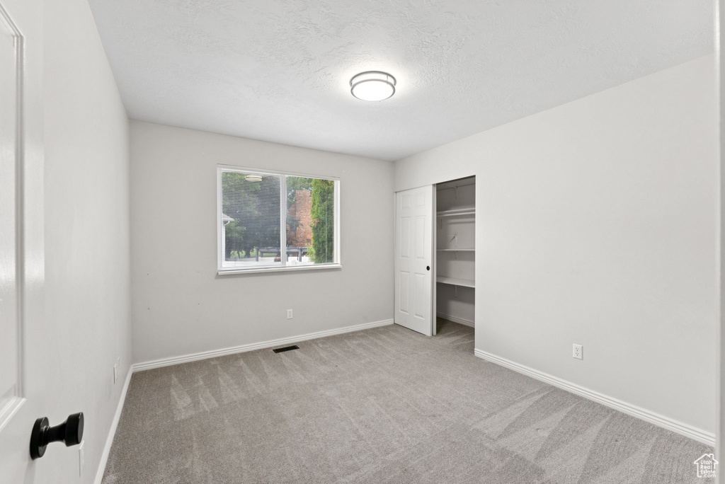 Unfurnished bedroom with carpet floors, a textured ceiling, and a closet