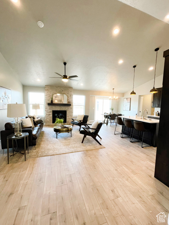 Living room with a fireplace, healthy amount of natural light, ceiling fan, light wood-type flooring, and lofted ceiling