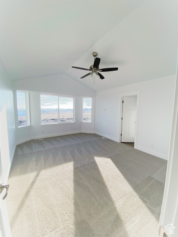 Spare room featuring carpet, lofted ceiling, and a ceiling fan