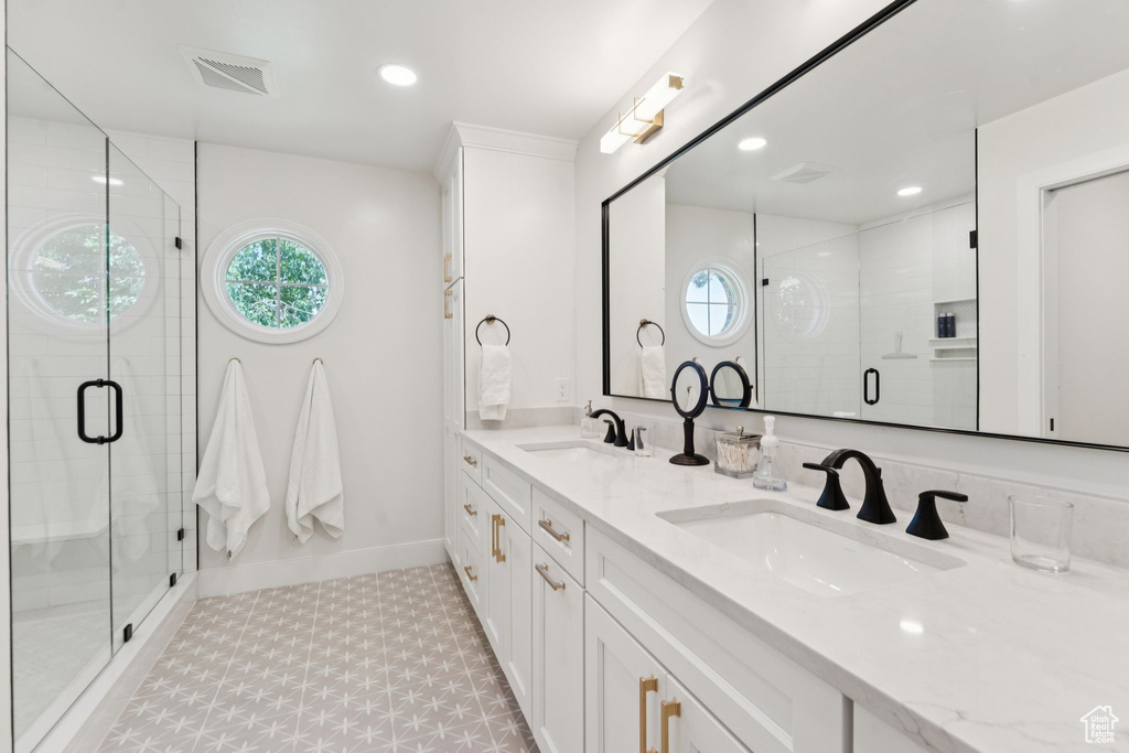 Bathroom with healthy amount of natural light, double vanity, a shower stall, recessed lighting, and tile patterned floors