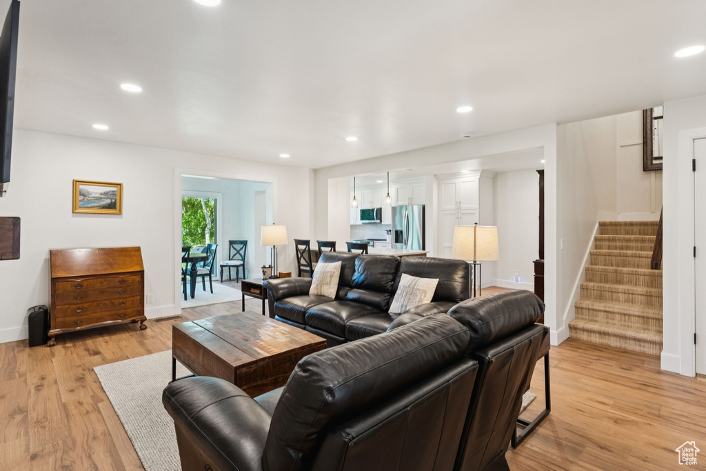 Living room with stairs, light wood finished floors, and recessed lighting
