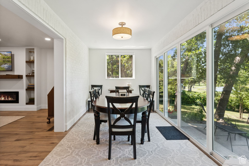 Dining room with wood finished floors and a lit fireplace