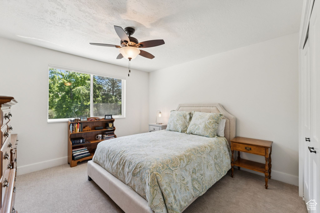 Bedroom with light colored carpet, a closet, and ceiling fan