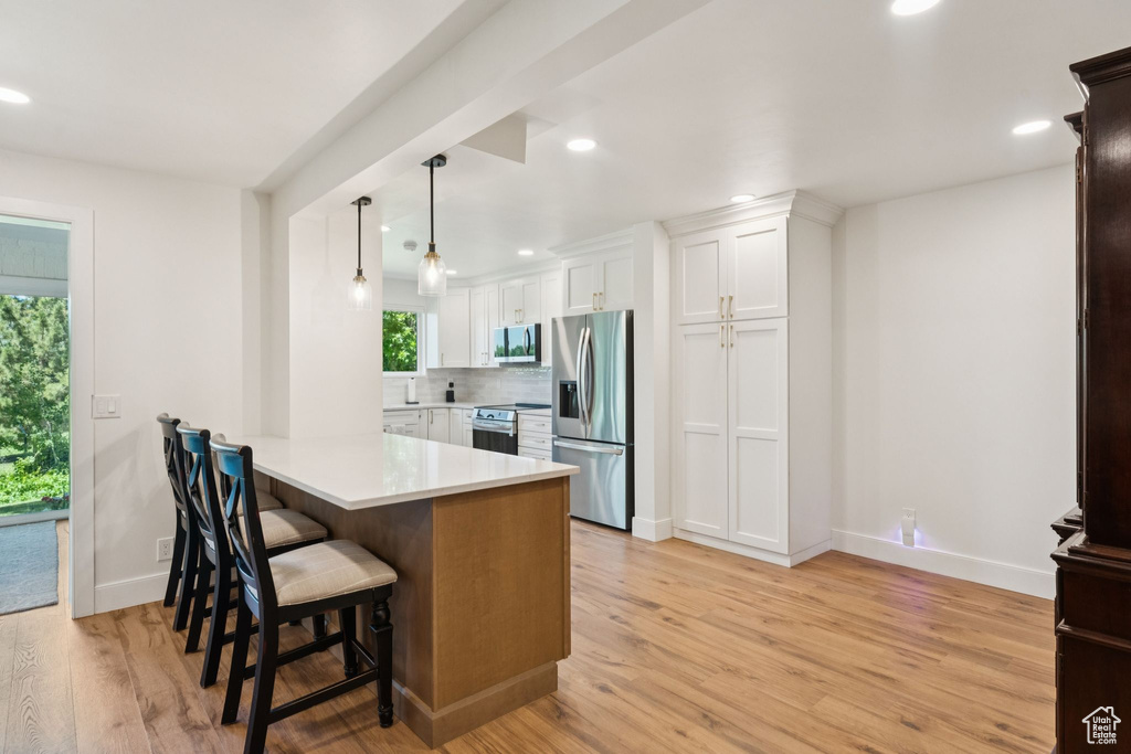 Kitchen with appliances with stainless steel finishes, healthy amount of natural light, white cabinetry, light countertops, and recessed lighting