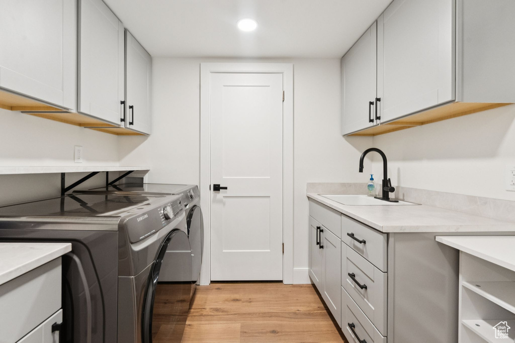 Laundry area with cabinet space, washer and dryer, light wood-type flooring, and recessed lighting