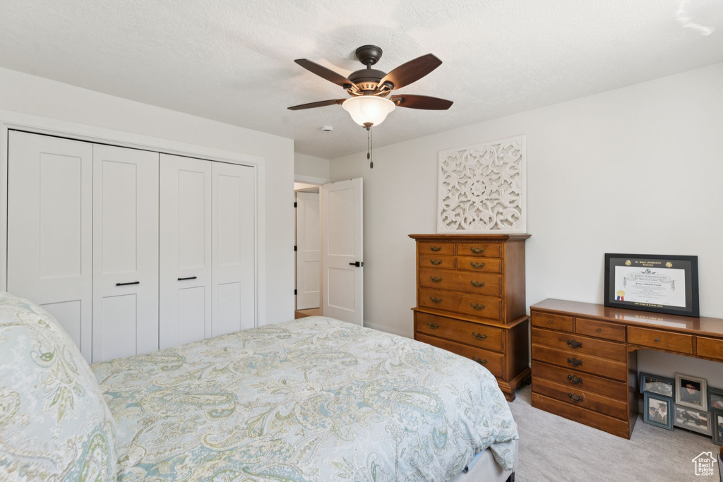Carpeted bedroom featuring a closet and a ceiling fan