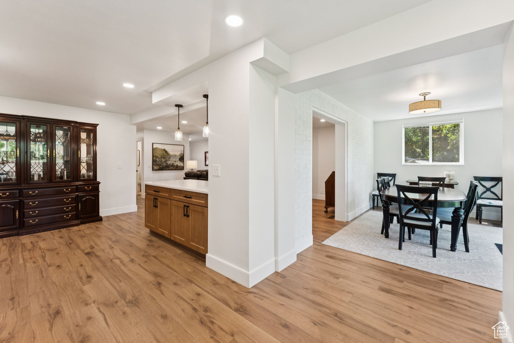 Kitchen with light wood-type flooring, light countertops, recessed lighting, and hanging light fixtures