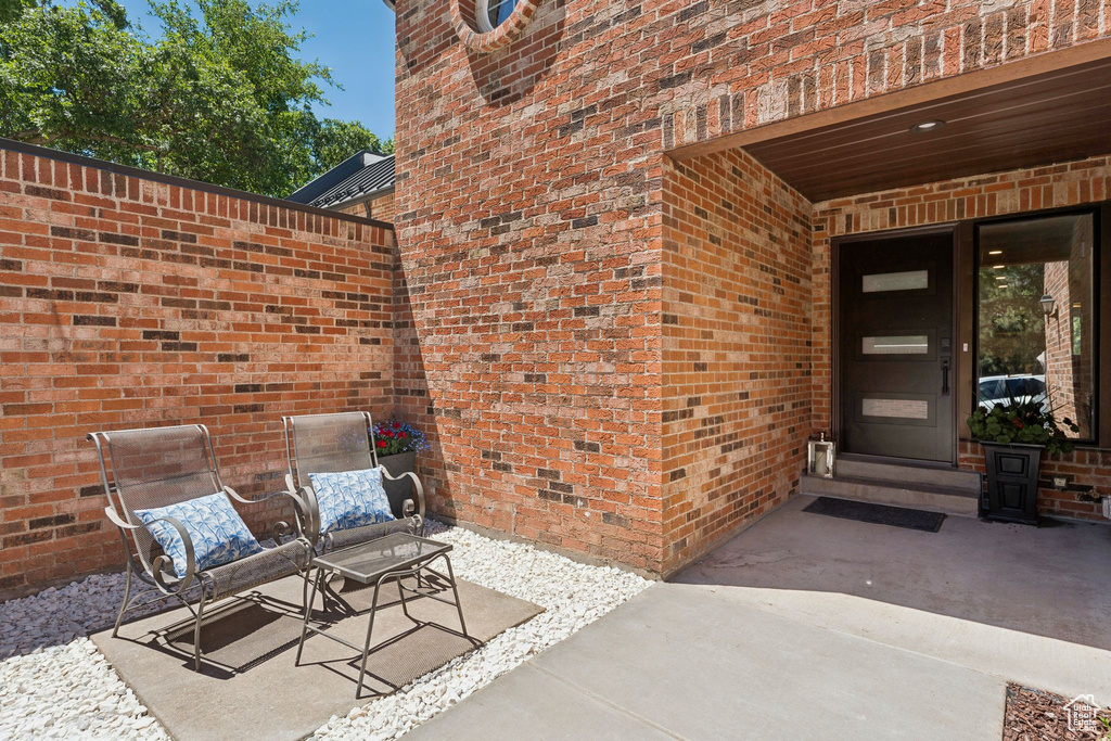 Entrance to property with brick siding and a patio area