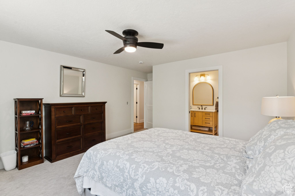 Bedroom featuring light colored carpet, a ceiling fan, and connected bathroom