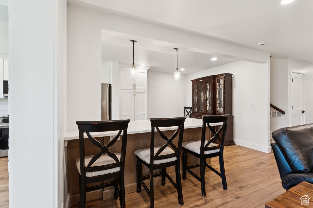 Bar area featuring light wood finished floors, recessed lighting, stove, freestanding refrigerator, and pendant lighting