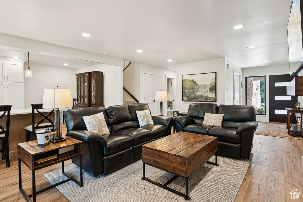 Living area with light wood finished floors, recessed lighting, and stairs