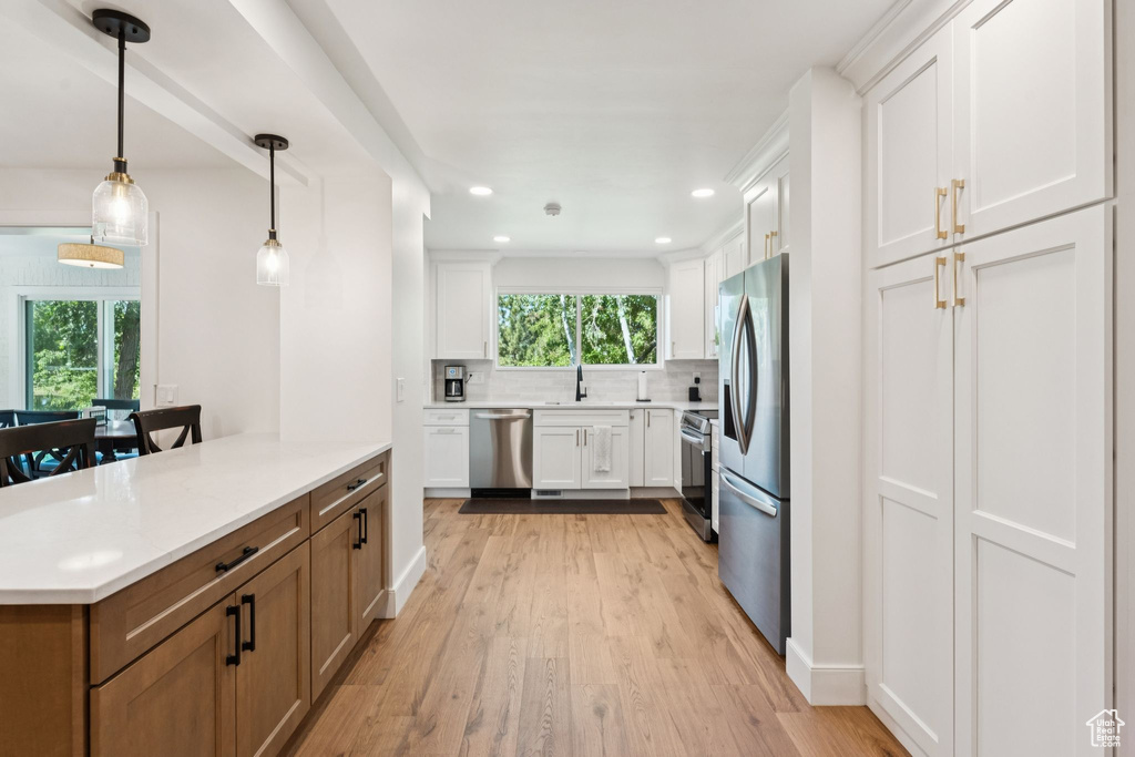 Kitchen featuring appliances with stainless steel finishes, healthy amount of natural light, light wood-style floors, decorative backsplash, and recessed lighting