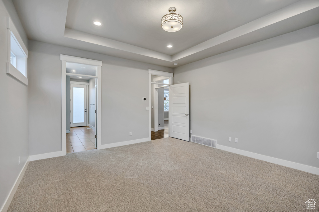 Unfurnished bedroom with recessed lighting, carpet flooring, and a raised ceiling