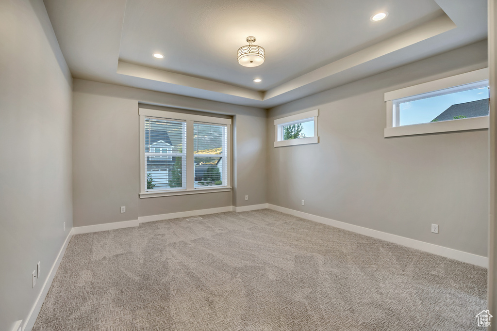 Carpeted spare room featuring a raised ceiling and recessed lighting