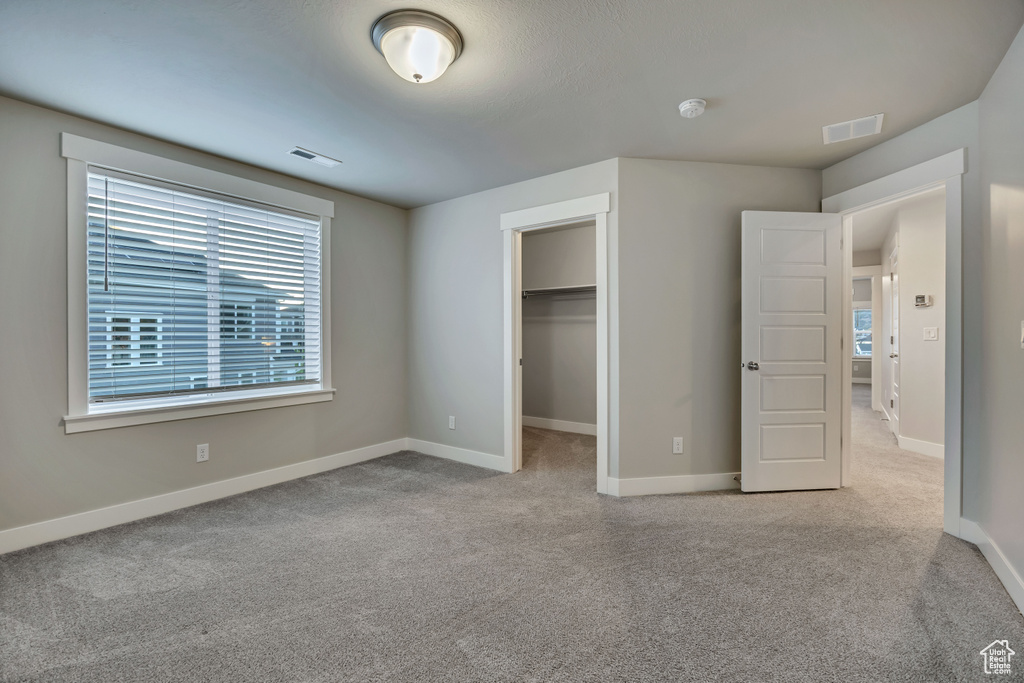 Unfurnished bedroom featuring carpet floors, a spacious closet, and a closet