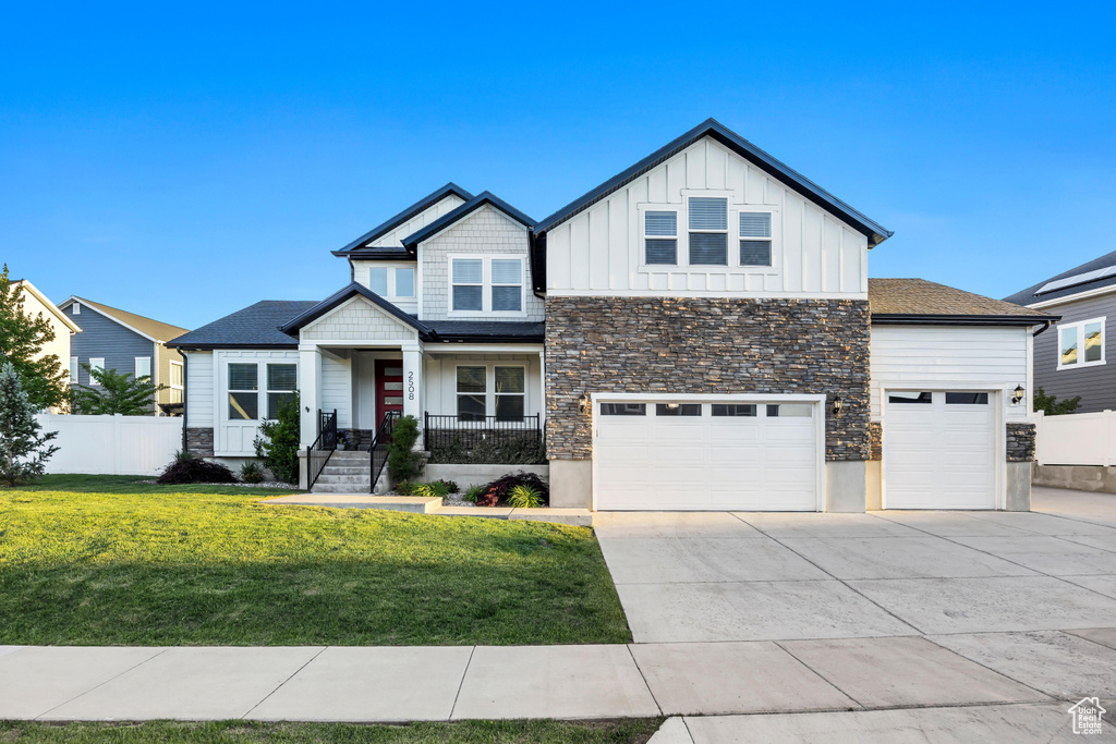 View of front facade with board and batten siding, concrete driveway, stone siding, a garage, and a porch