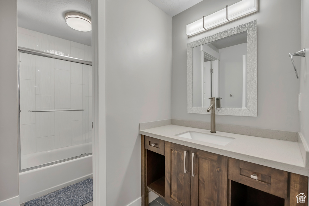 Bathroom featuring vanity and shower / bath combination with glass door