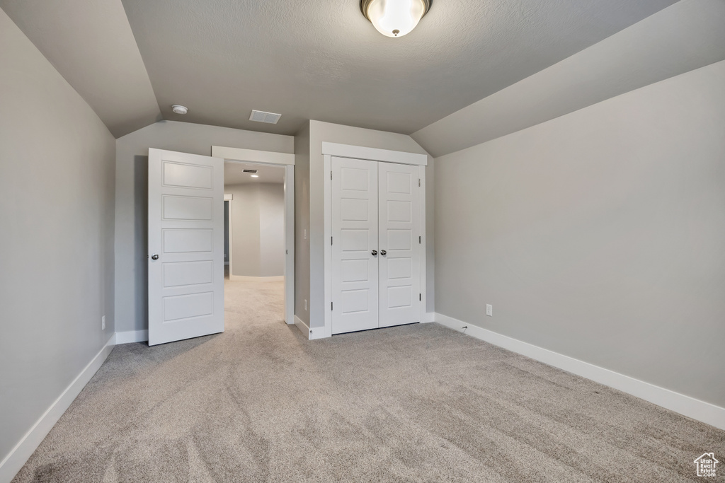 Unfurnished bedroom featuring lofted ceiling, carpet floors, and a closet