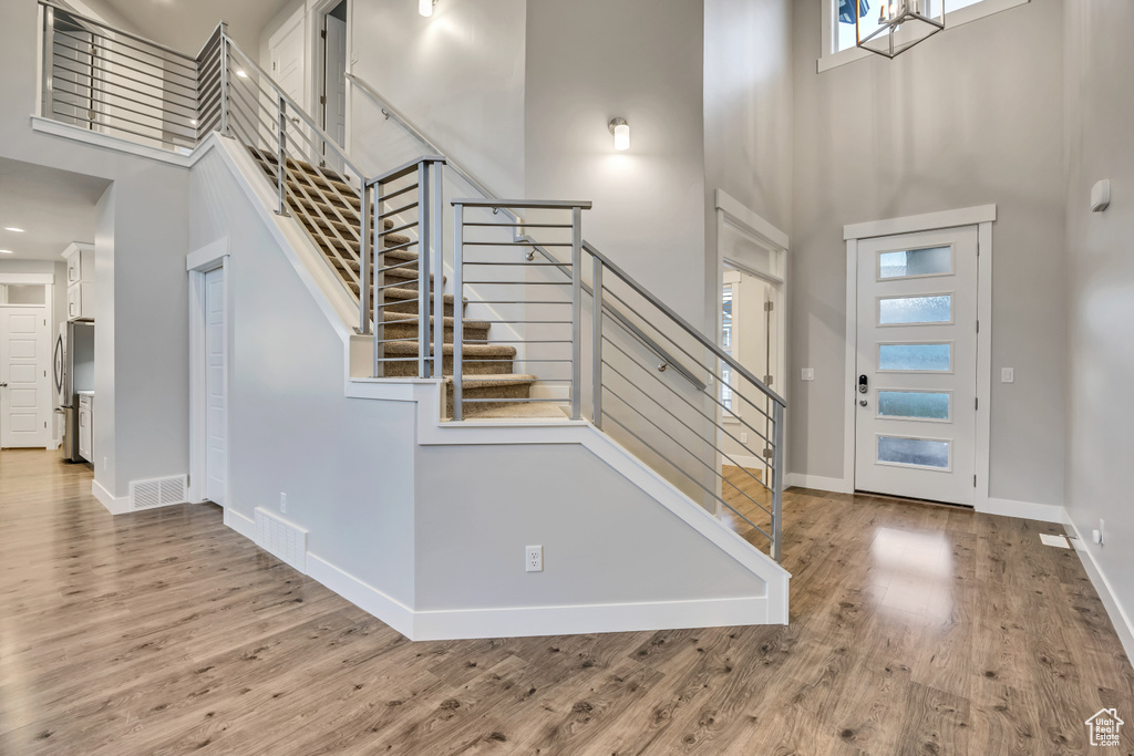 Foyer with a high ceiling, stairway, wood finished floors, and recessed lighting