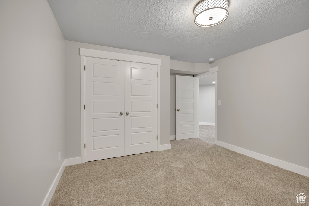 Unfurnished bedroom featuring carpet floors, a closet, and a textured ceiling
