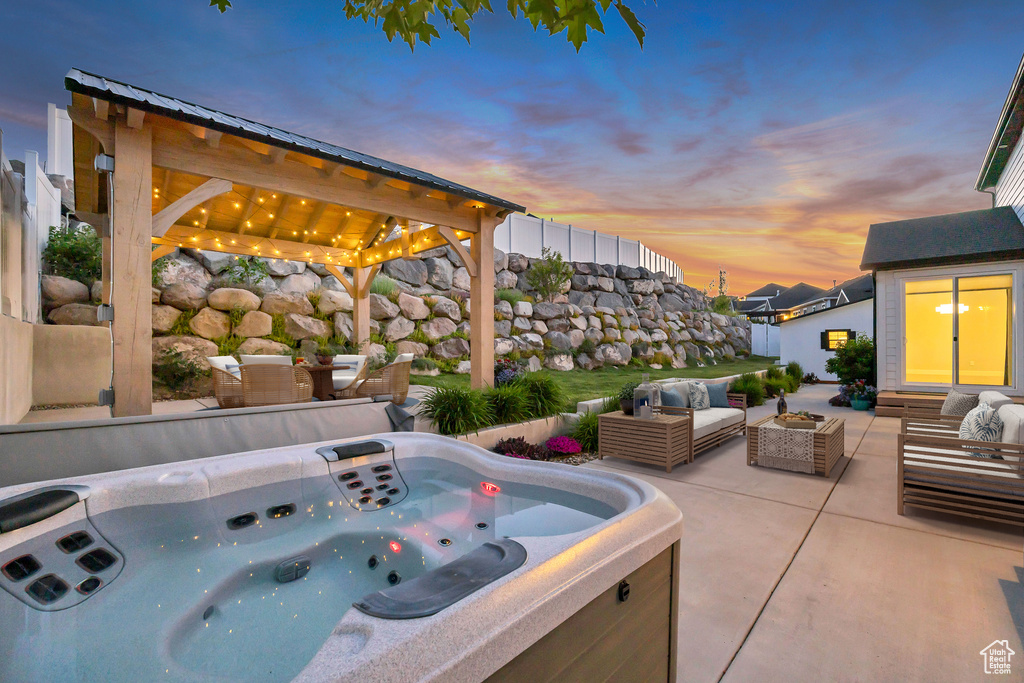 Patio terrace at dusk featuring a patio area, an outdoor living space, a gazebo, and a hot tub
