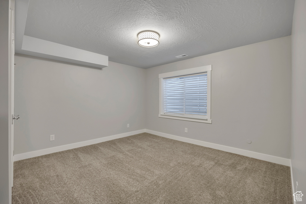 Empty room with a textured ceiling and carpet floors