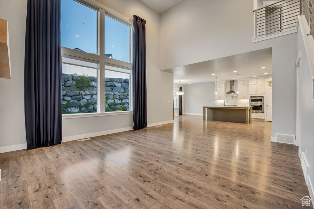 Unfurnished living room featuring a high ceiling and wood finished floors