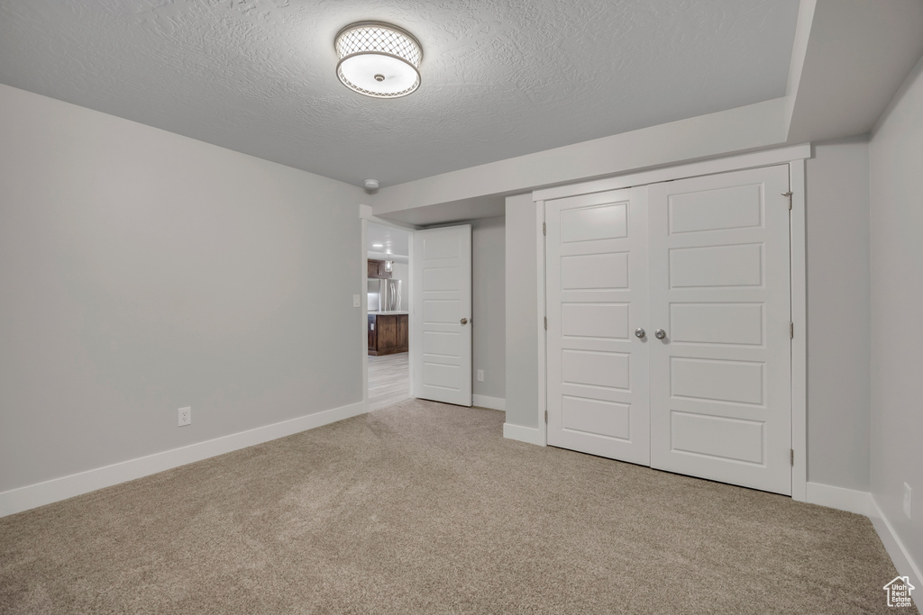 Unfurnished bedroom with carpet floors, a textured ceiling, and a closet